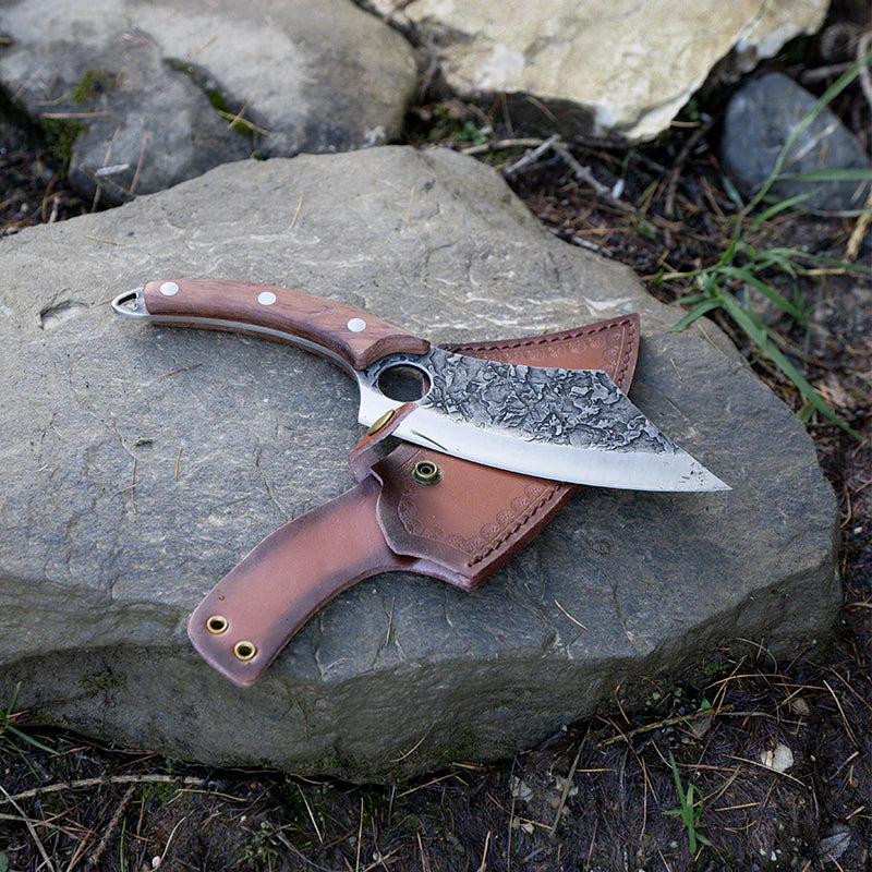 Side-by-side display of a bearded man dressed as a Viking and a uniquely crafted Viking knife resting on a rock. The knife features a patterned steel blade and a leather sheath, representing the Loki Series – a blend of Norse heritage, handmade precision, and bold Viking style. Ideal for collectors, adventurers, and those seeking the best gift knife or handmade Viking knife with unmatched character.