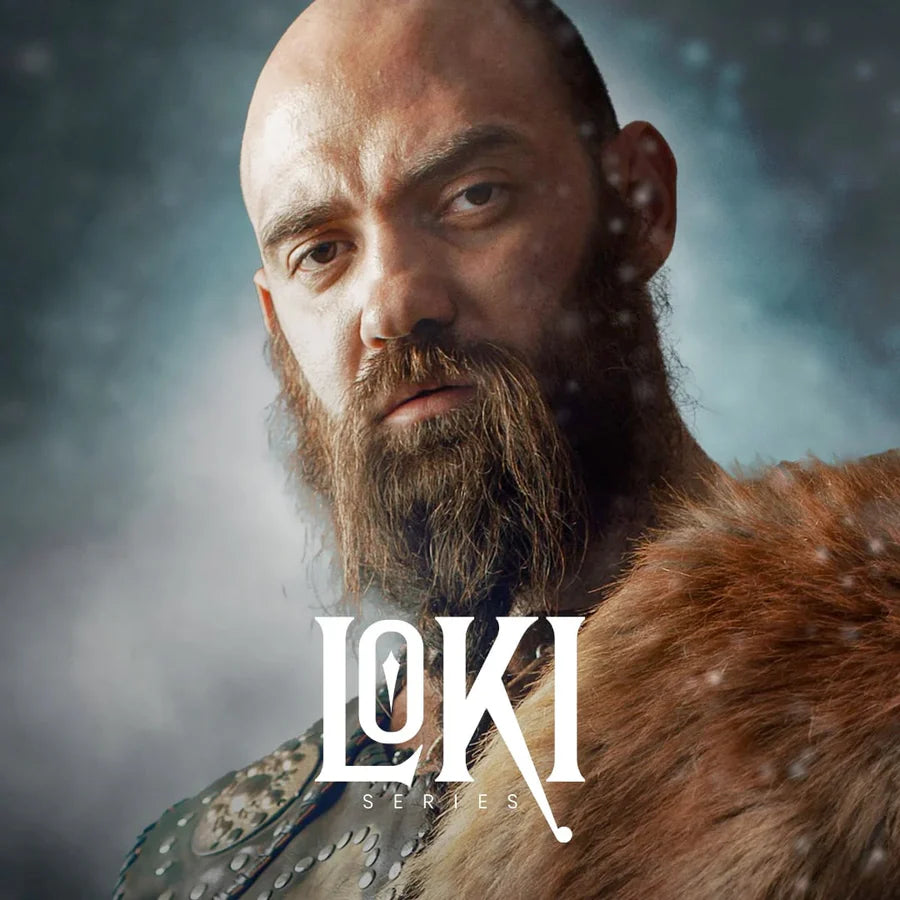 Side-by-side display of a bearded man dressed as a Viking and a uniquely crafted Viking knife resting on a rock. The knife features a patterned steel blade and a leather sheath, representing the Loki Series – a blend of Norse heritage, handmade precision, and bold Viking style. Ideal for collectors, adventurers, and those seeking the best gift knife or handmade Viking knife with unmatched character.